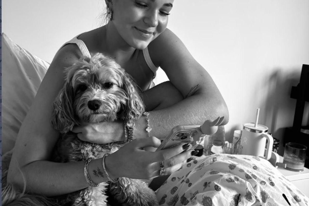 Ruby sitting on a bed beside a dog.
