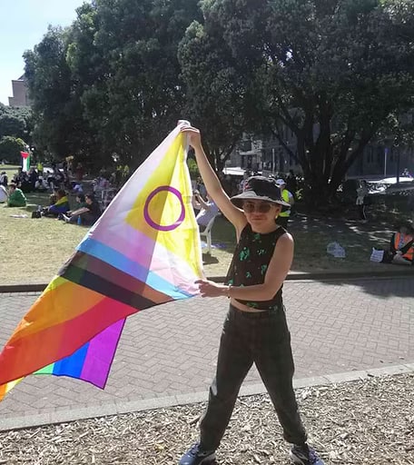 River, Youth Advisory Board member, holding an inclusive Pride flag